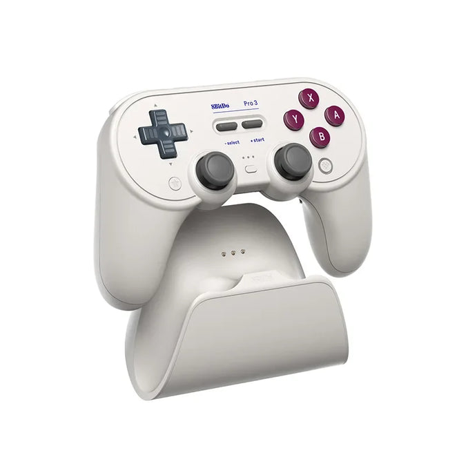 Light-colored 8BitDo Pro 3 with symmetrical lower sticks on its matching dock.